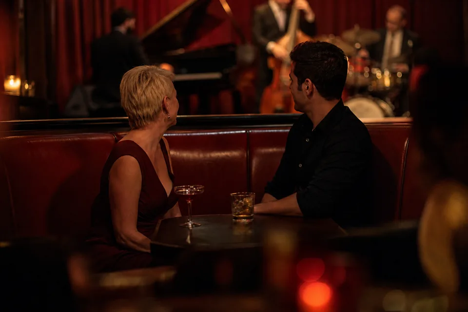 Woman and younger man sharing a booth at a small jazz club at night, illustrative photo, not a member