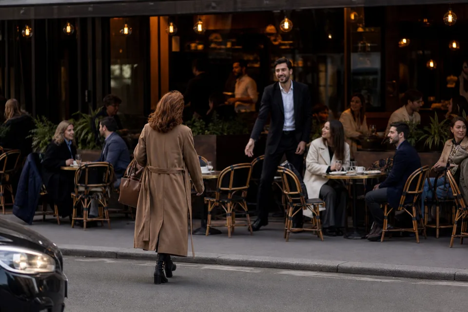 Woman arriving at a busy cafe terrace for a first meeting in daylight, illustrative photo, not a member